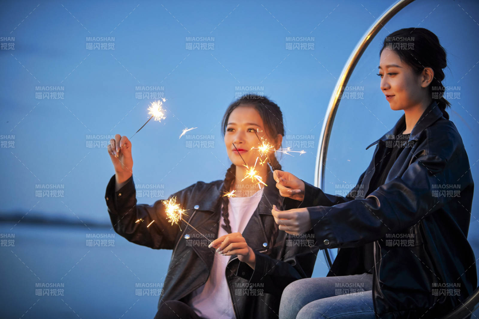 傍晚湖畔透明秋千上燃放仙女棒的可愛少女