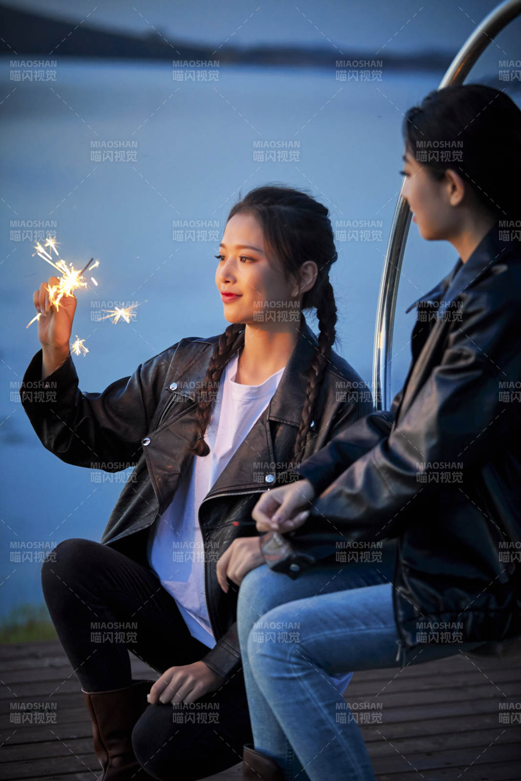 傍晚湖畔透明秋千上燃放仙女棒的可爱少女