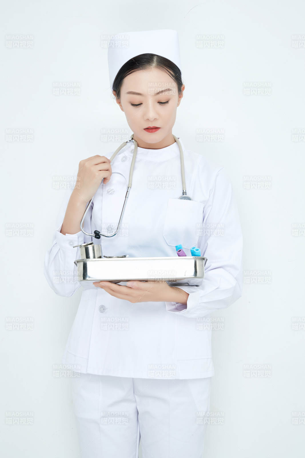 身穿护士服手抱化验托盘的年轻女护士