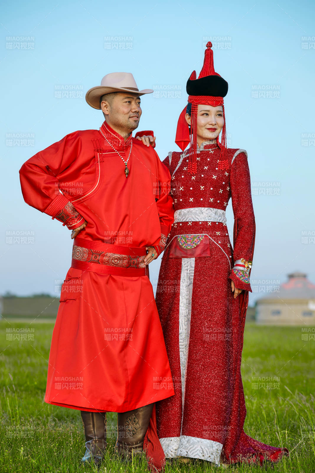 草原上蒙古包前穿蒙古族传统服饰的年轻夫妻