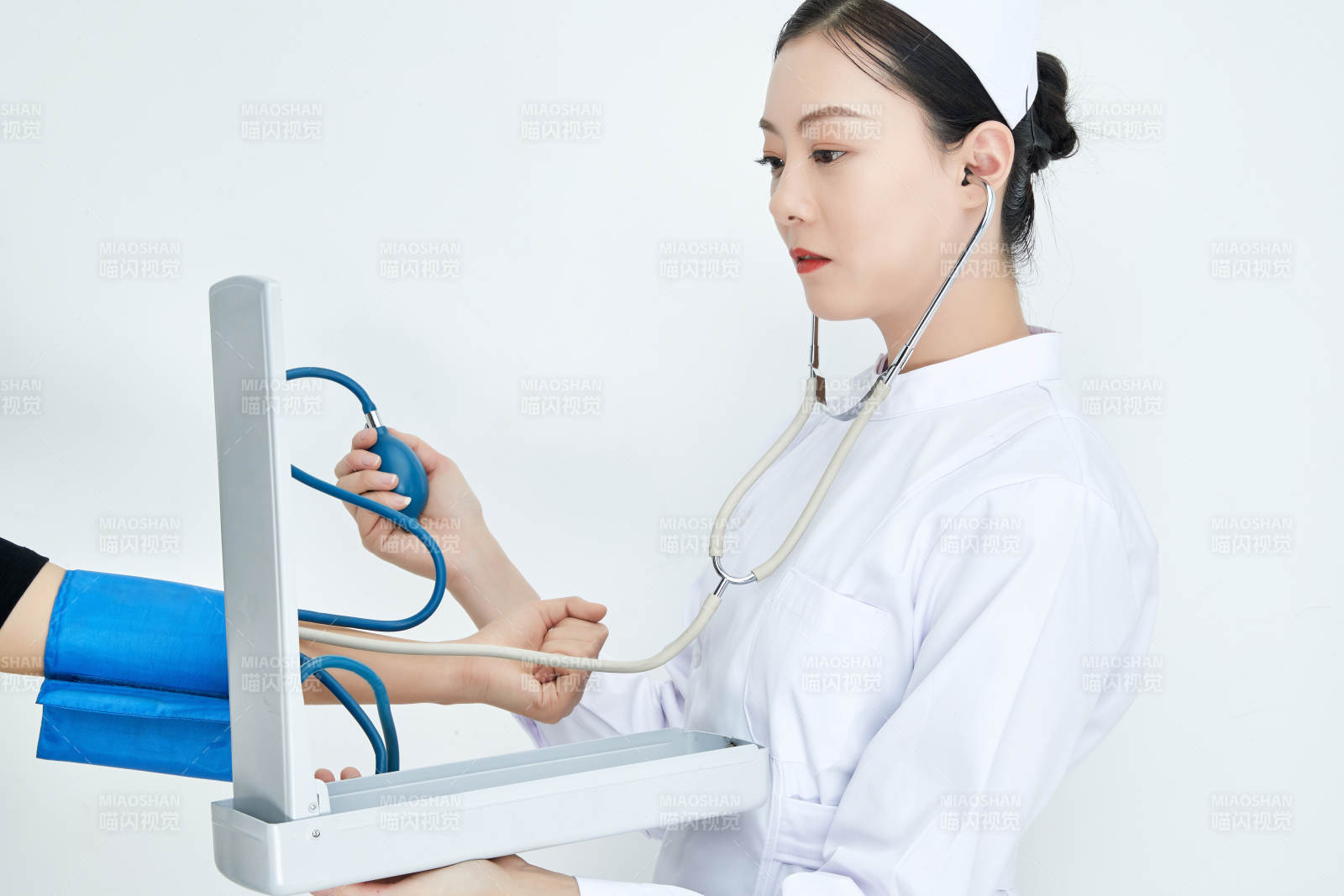白色背景下手持血壓計(jì)測(cè)量血壓的醫(yī)生