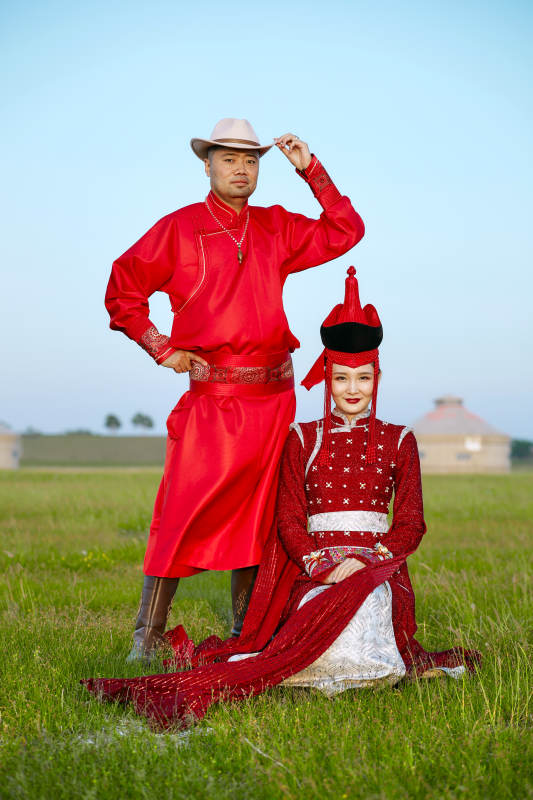 草原上蒙古包前穿蒙古族传统服饰的年轻夫妻