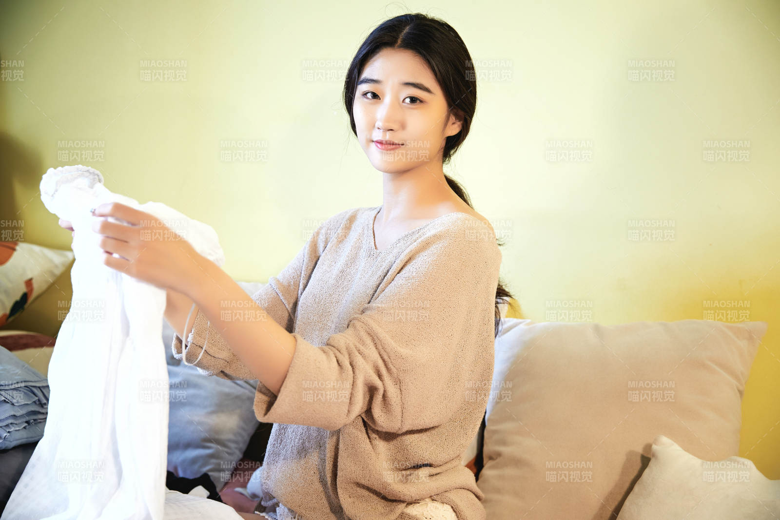 在沙發床上整理行裝的年輕亞洲女性