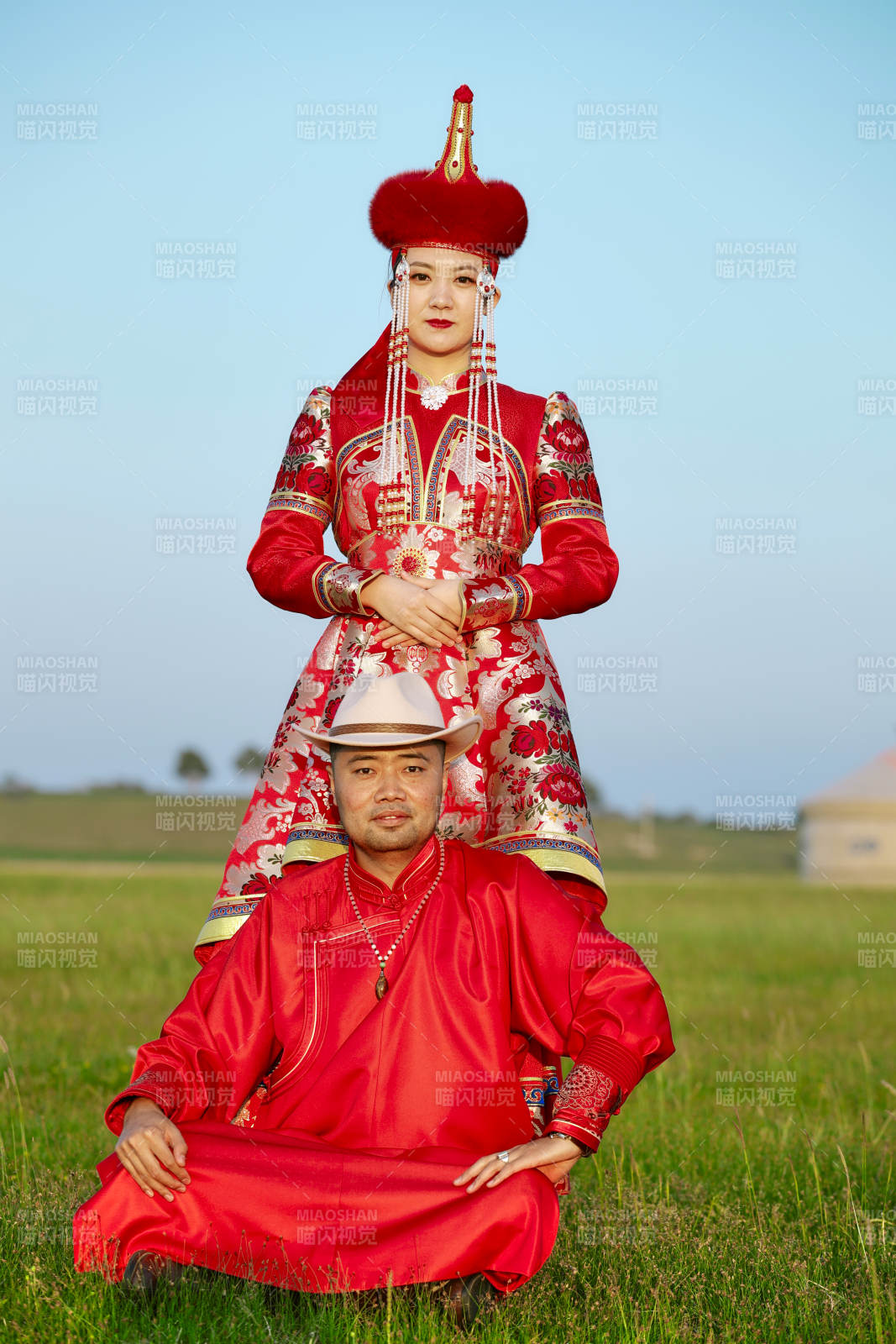 草原上蒙古包前穿蒙古族傳統服飾的年輕夫妻