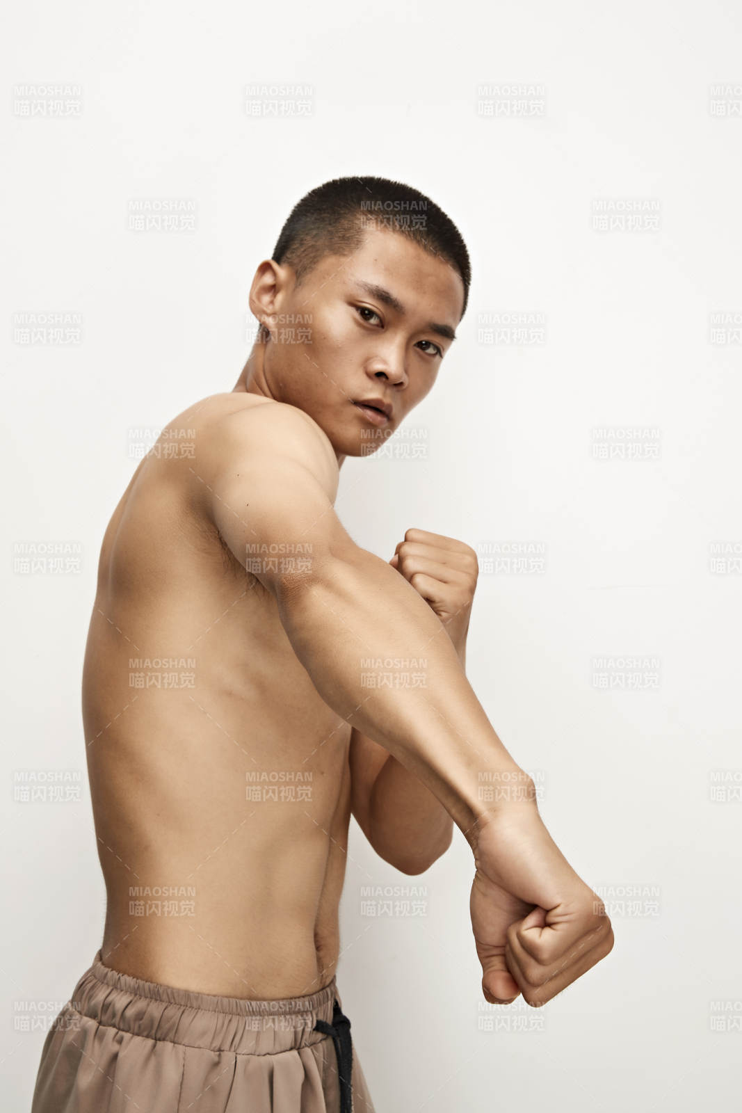 白色背景下演示自由搏擊動(dòng)作的亞洲功夫男性