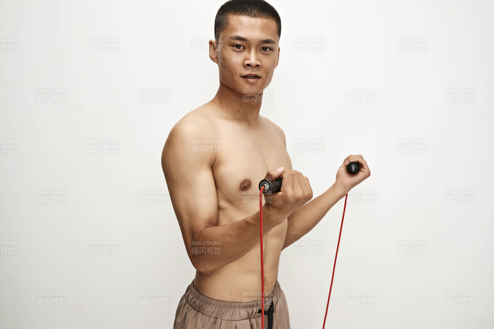 白色背景下手持運(yùn)動(dòng)跳繩的亞洲健身男士形象