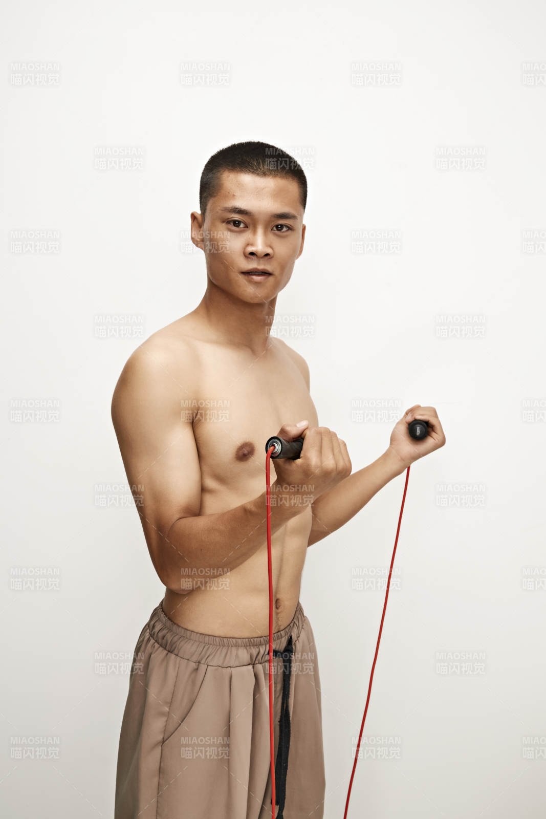 白色背景下手持運動跳繩的亞洲健身男士形象