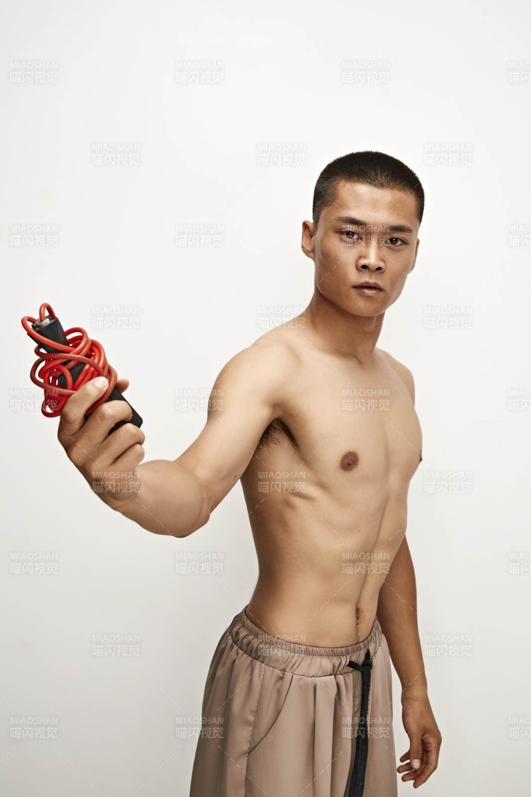 白色背景下手持運(yùn)動(dòng)跳繩的亞洲健身男士形象