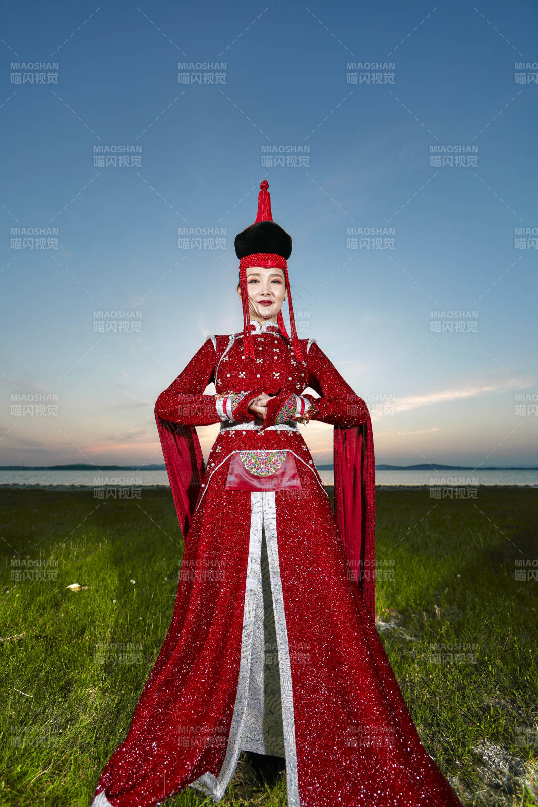 晚霞的草原湖畔穿蒙古族傳統服飾的年輕女性