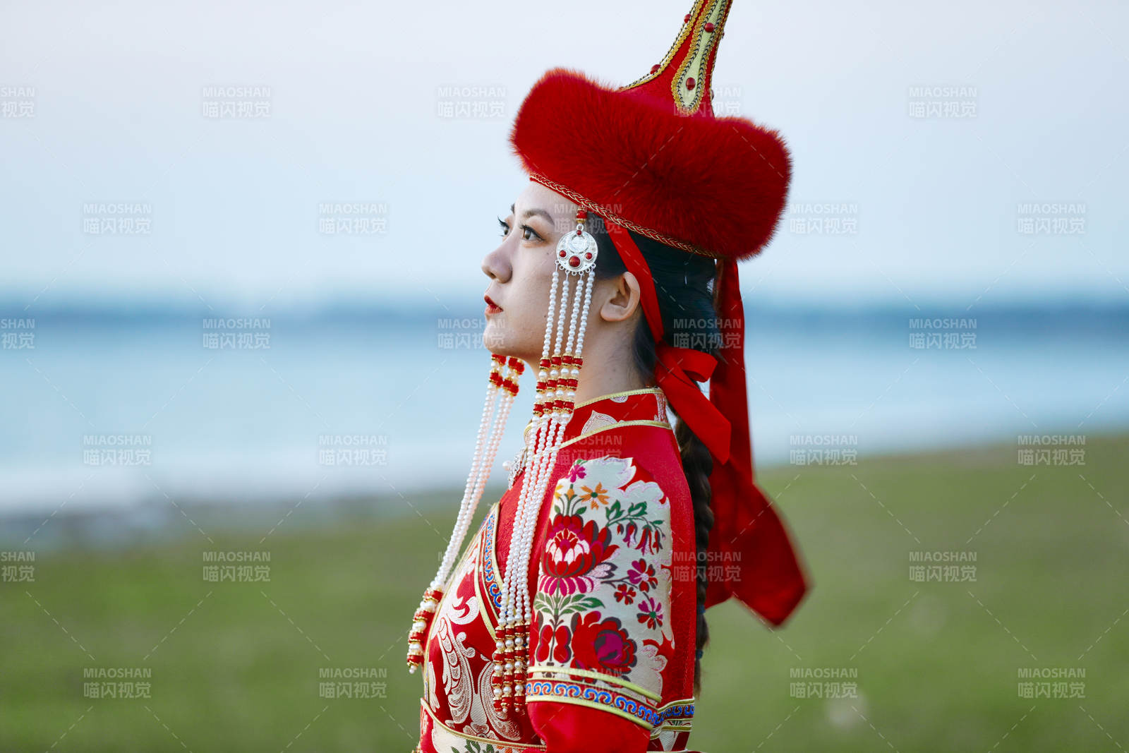 晚霞的草原湖畔穿蒙古族传统服饰的年轻女性