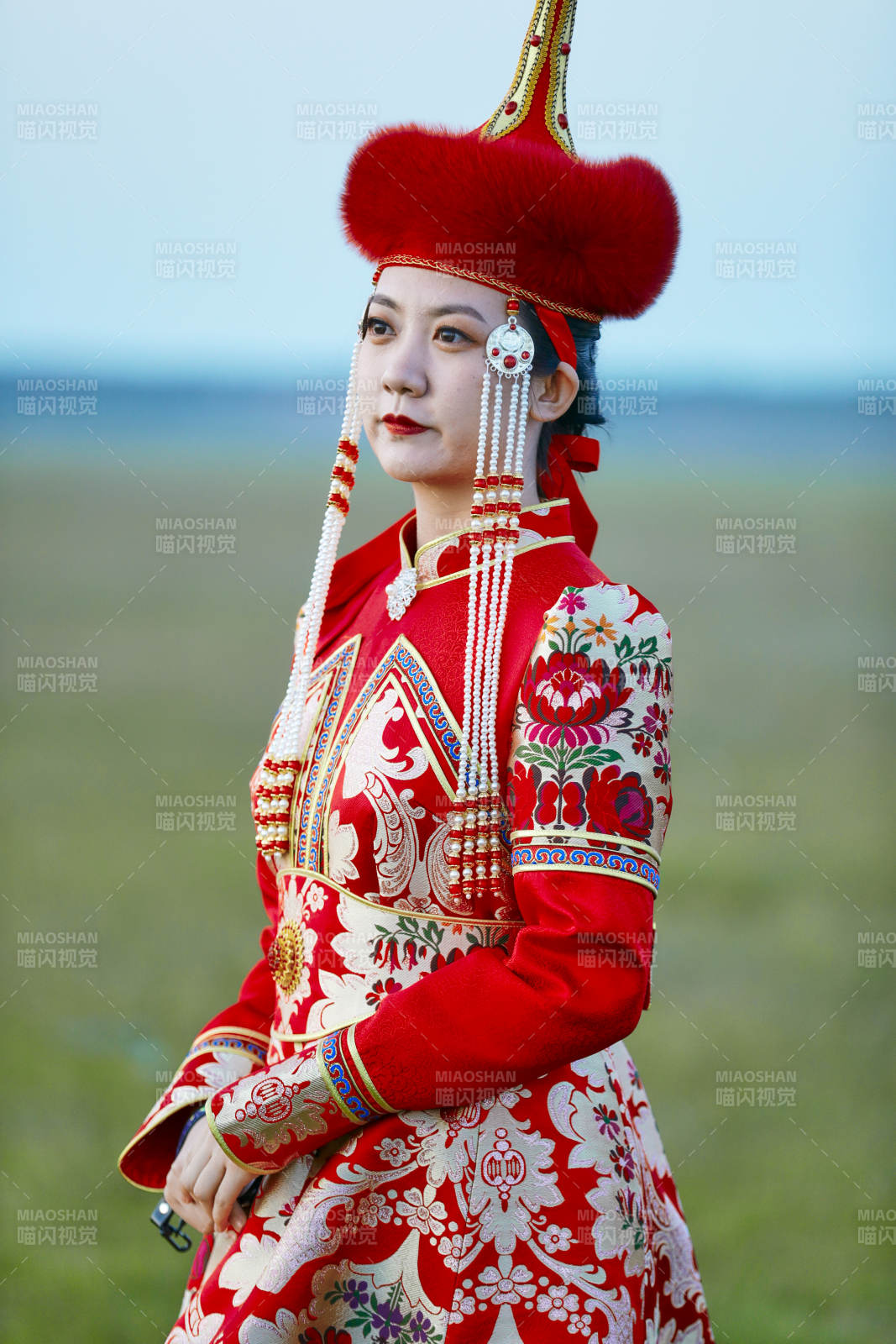 晚霞的草原湖畔穿蒙古族傳統服飾的年輕女性