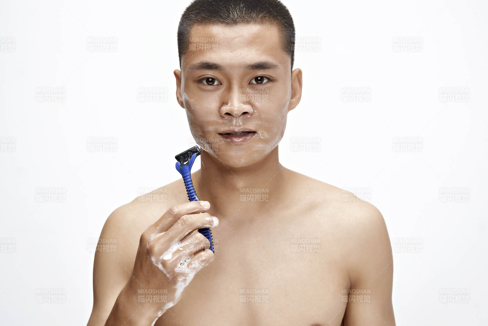 白色背景下手持剃須刀在刮胡子的亞洲男性