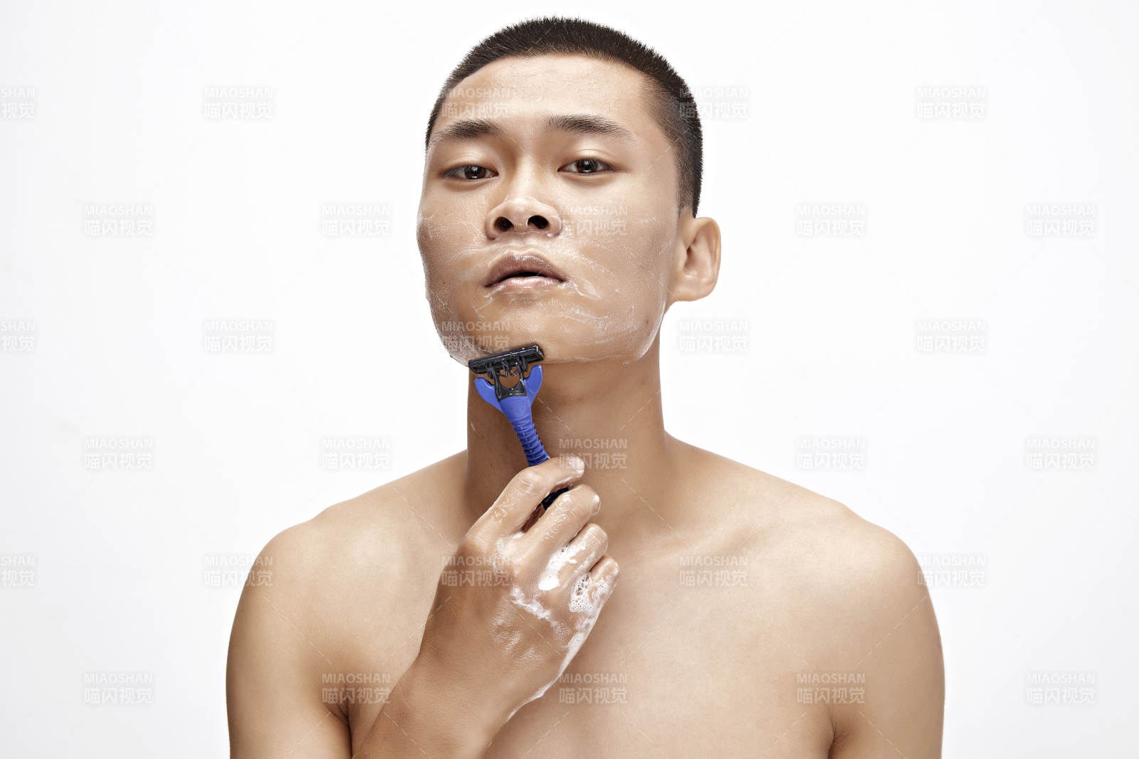 白色背景下手持剃須刀在刮胡子的亞洲男性