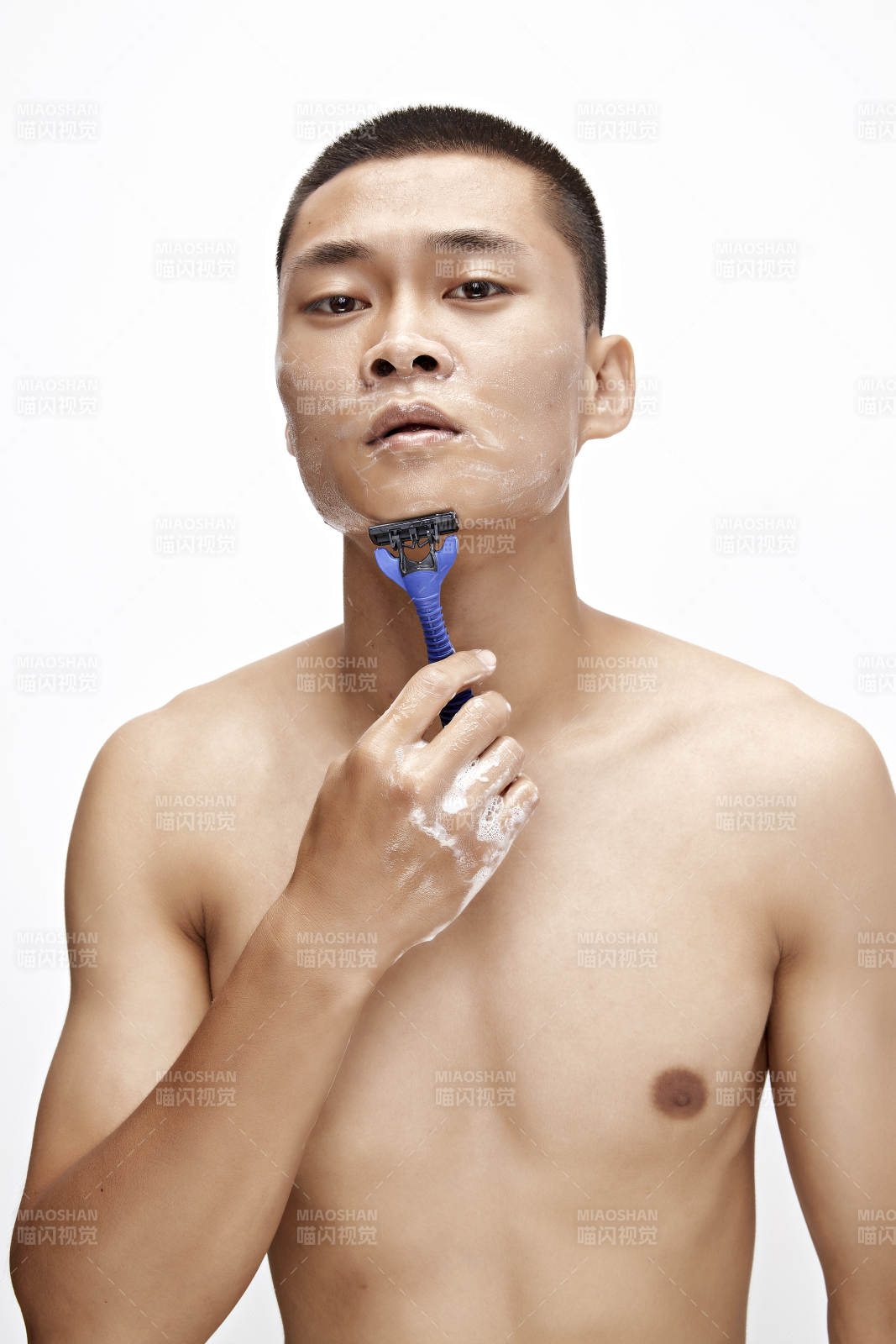 白色背景下手持剃須刀在刮胡子的亞洲男性