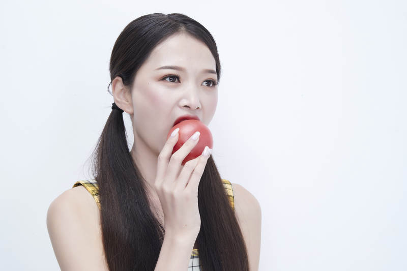 啃咬番茄身穿格子吊带裙的亚洲可爱少女人像