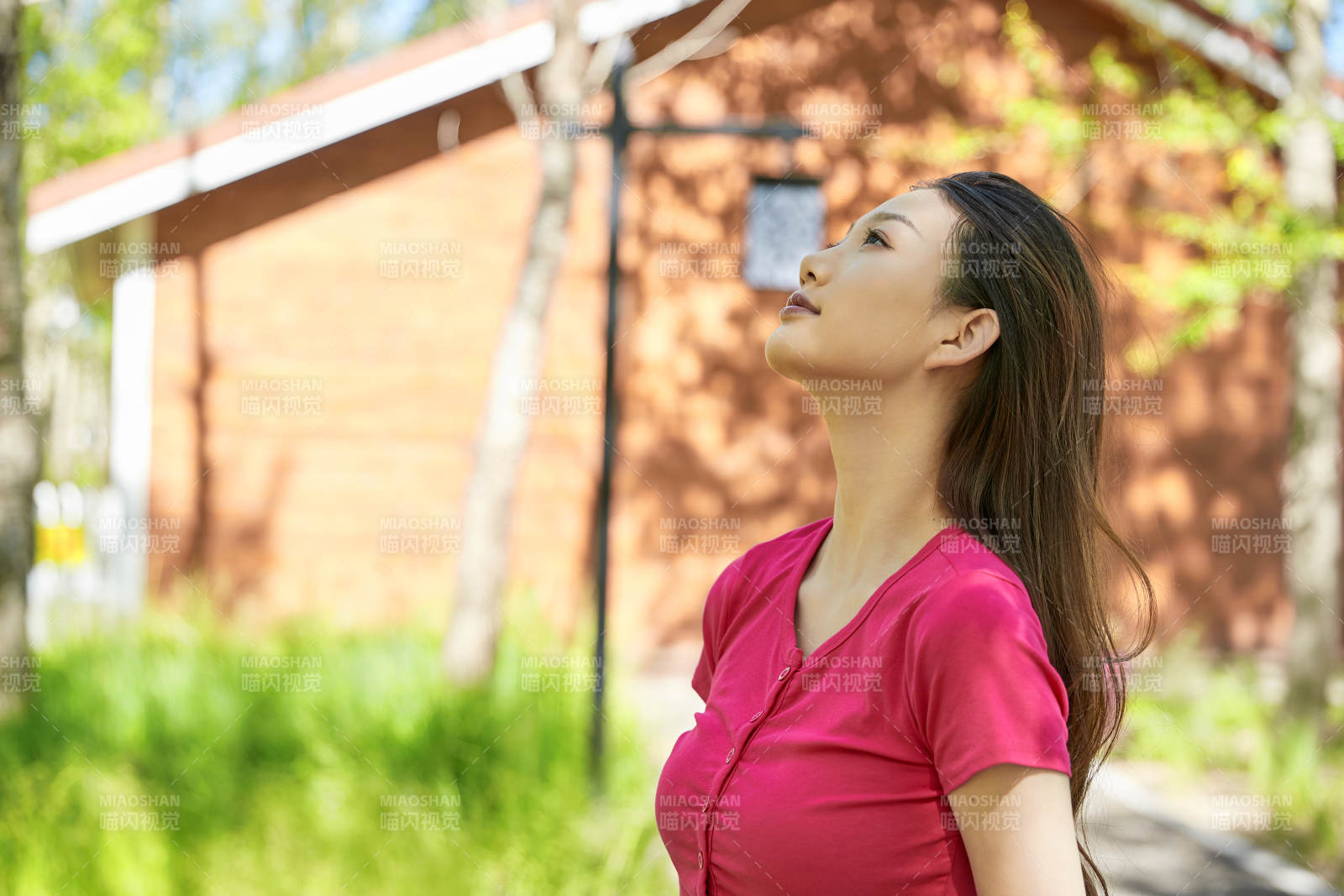 站在绿草如茵的木屋别墅群外的东方美女