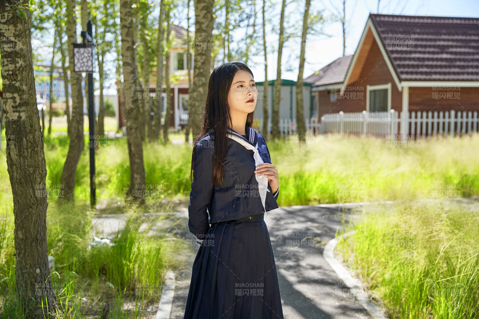 站在綠草如茵的木屋別墅群外的東方美女