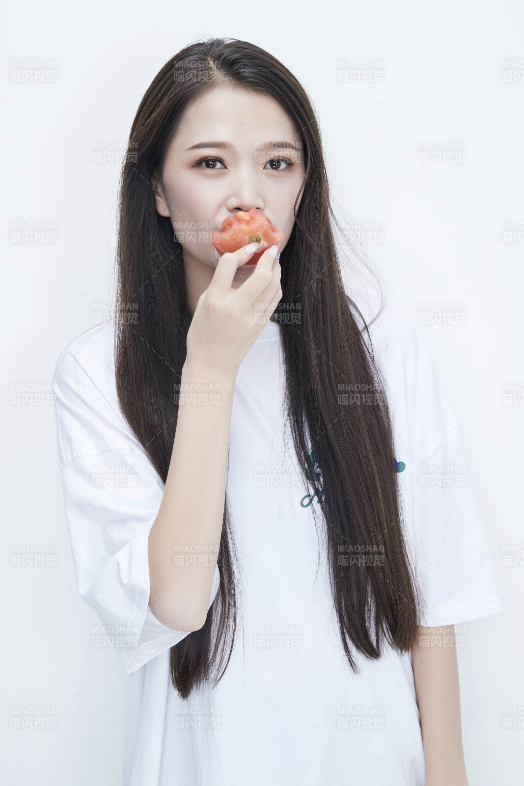 吃番茄的身穿白色長T血襯衫的長發少女人像