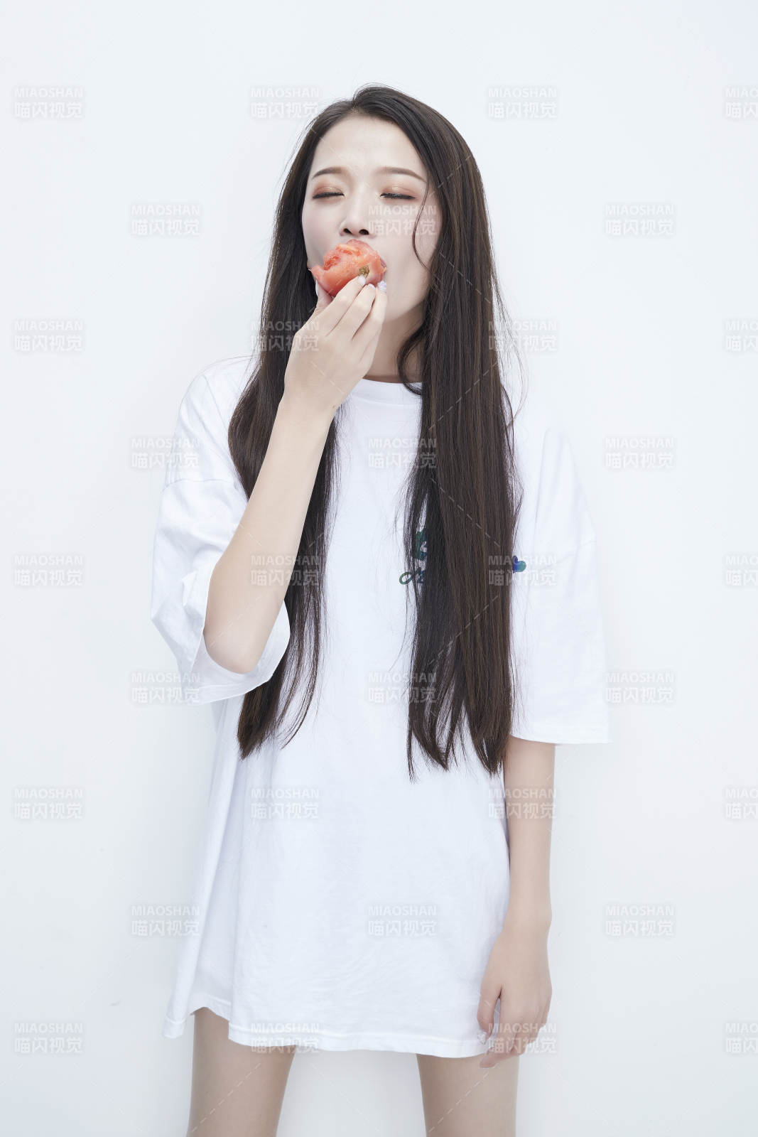 吃番茄的身穿白色長T血襯衫的長發少女人像