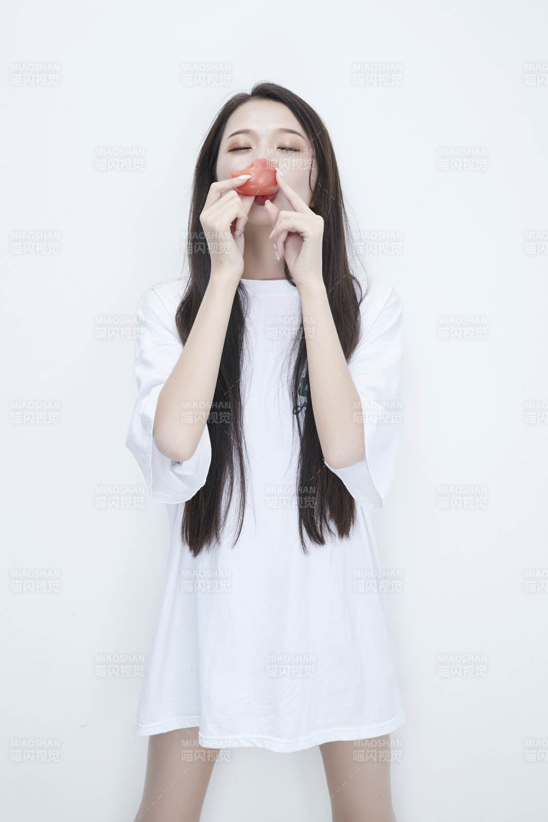 吃番茄的身穿白色長T血襯衫的長發少女人像