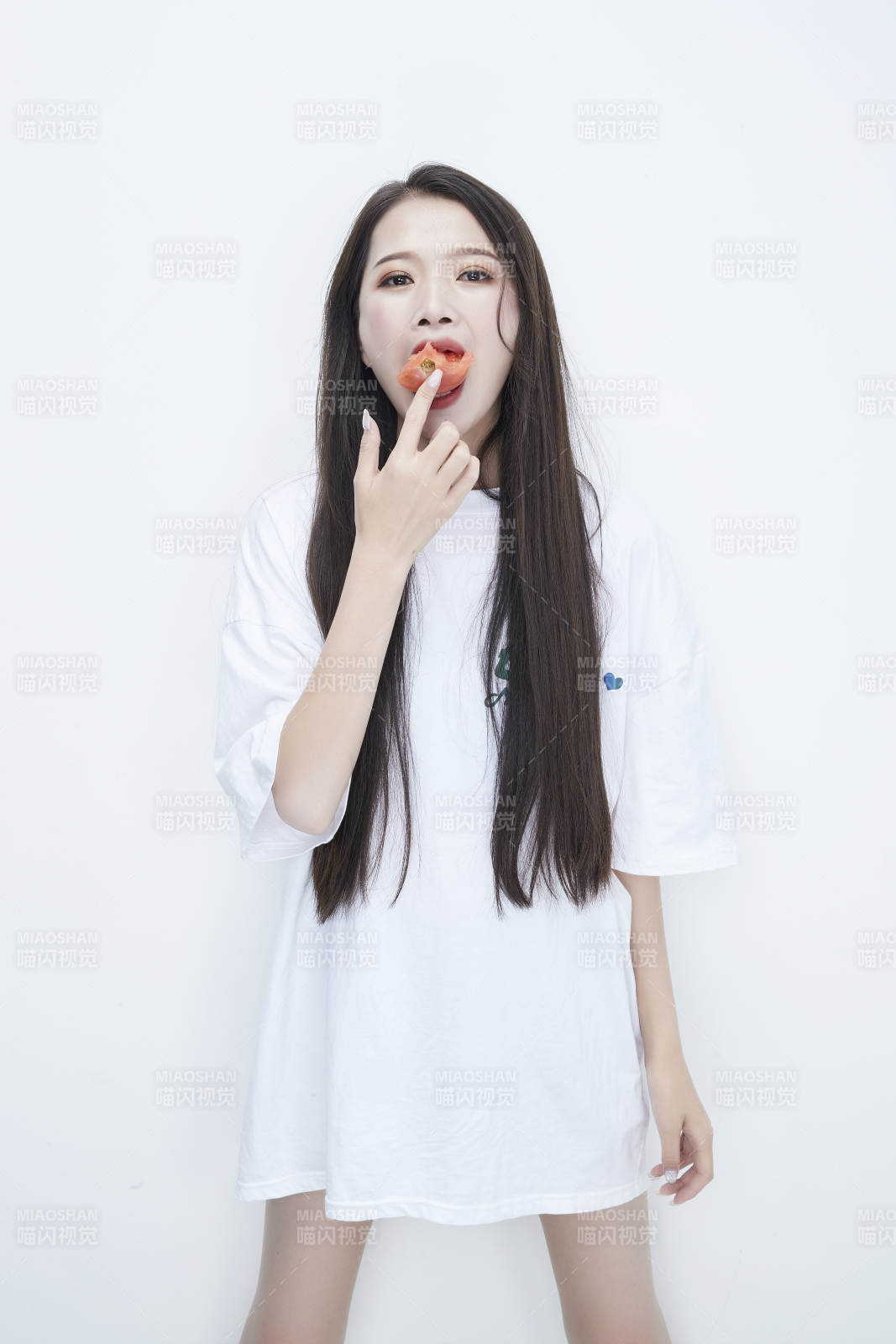 吃番茄的身穿白色長T血襯衫的長發少女人像
