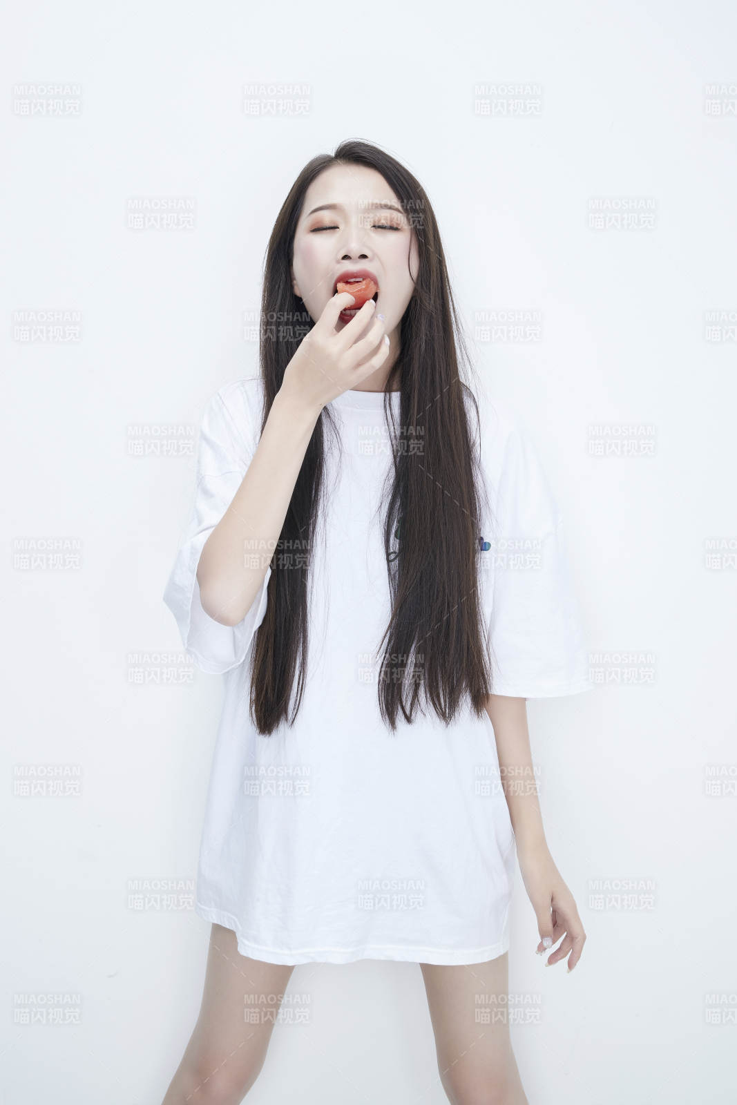 吃番茄的身穿白色長T血襯衫的長發少女人像