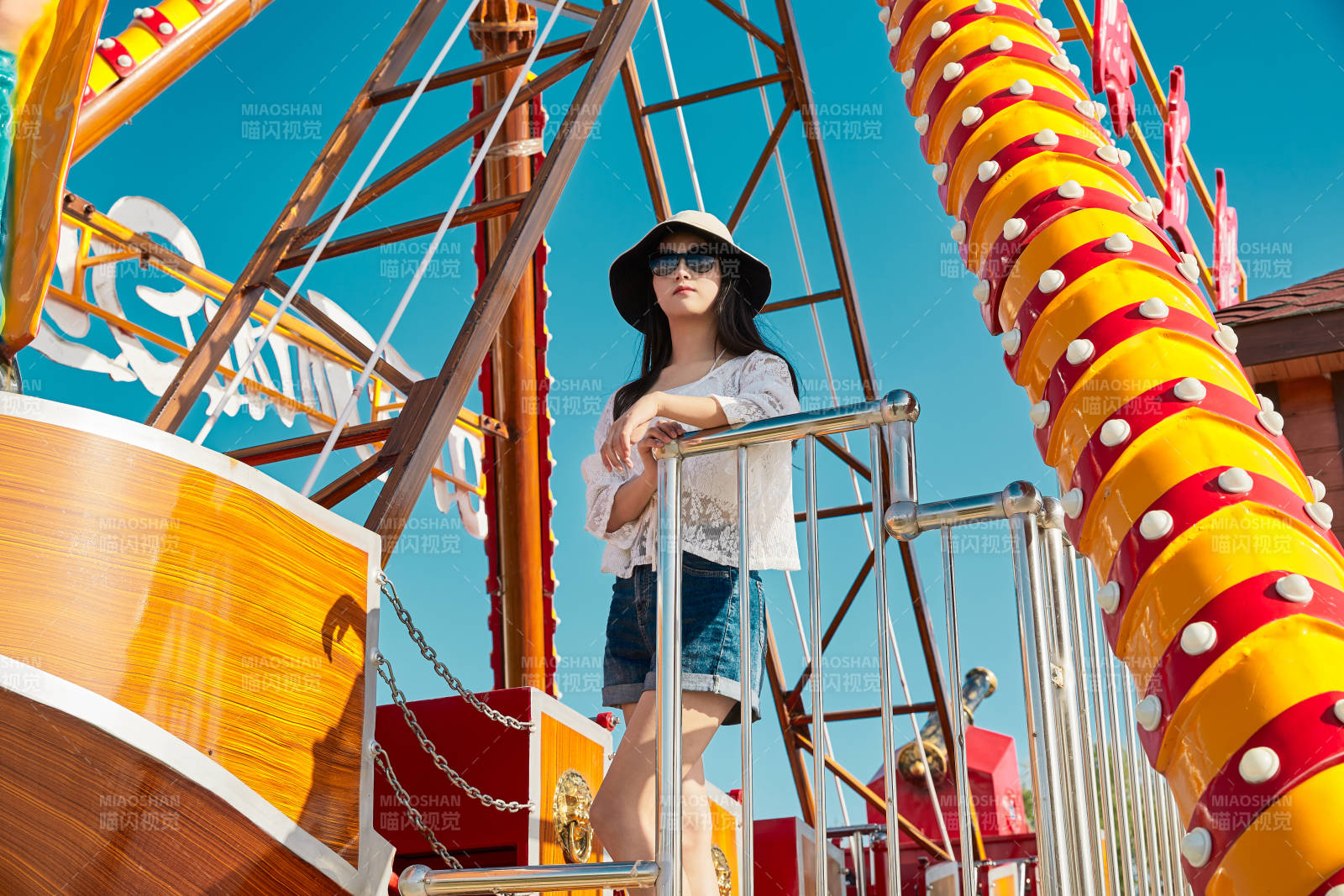 站在游樂場海盜船旁邊的美女