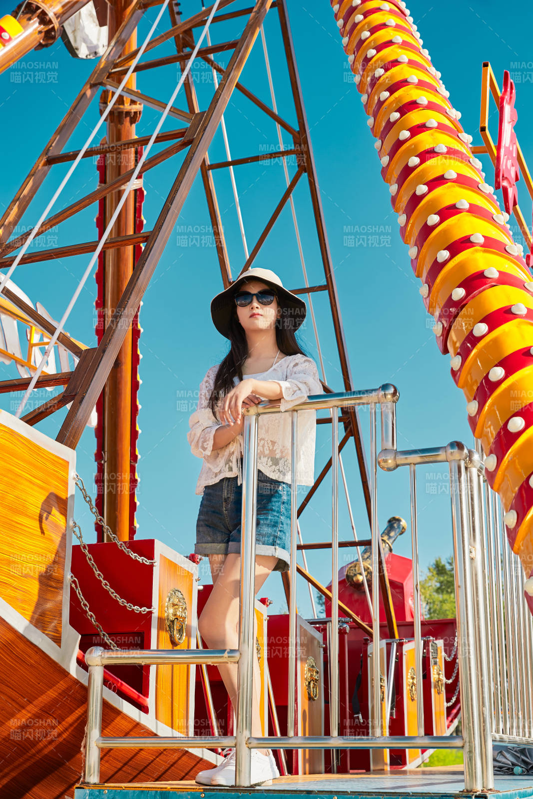 站在游樂場海盜船旁邊的美女
