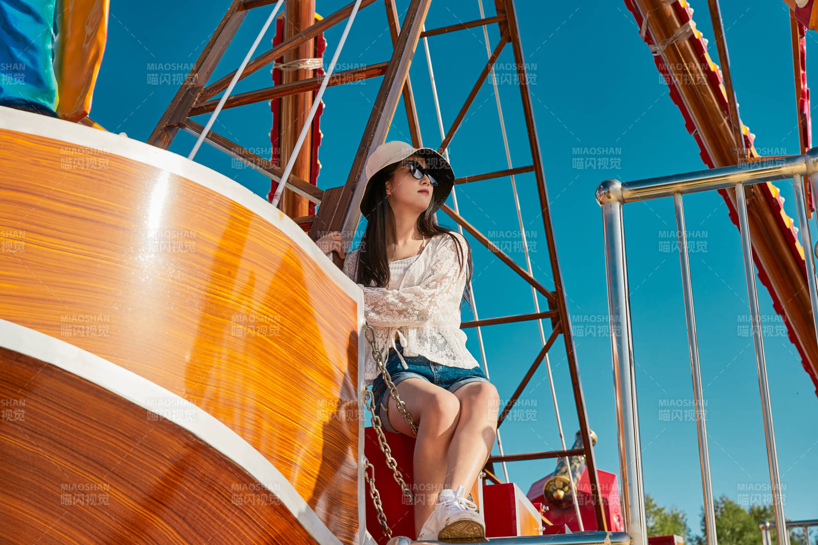 站在游樂場海盜船旁邊的美女