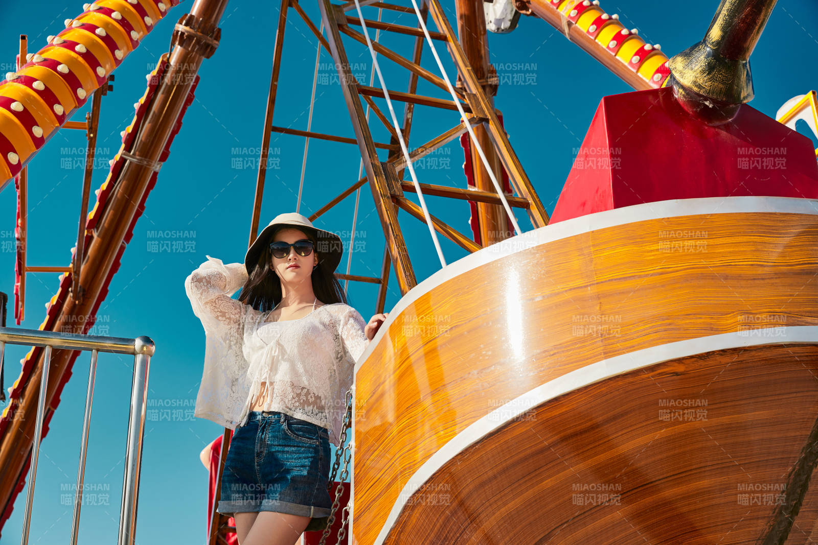站在游樂場海盜船旁邊的美女