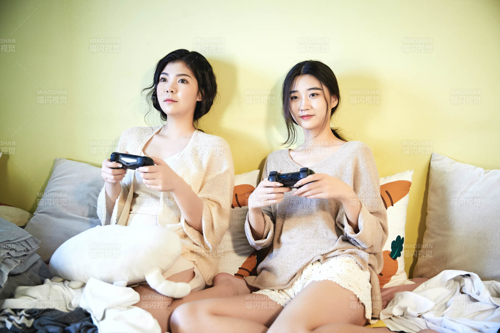 坐在床上打電玩的倆位美女