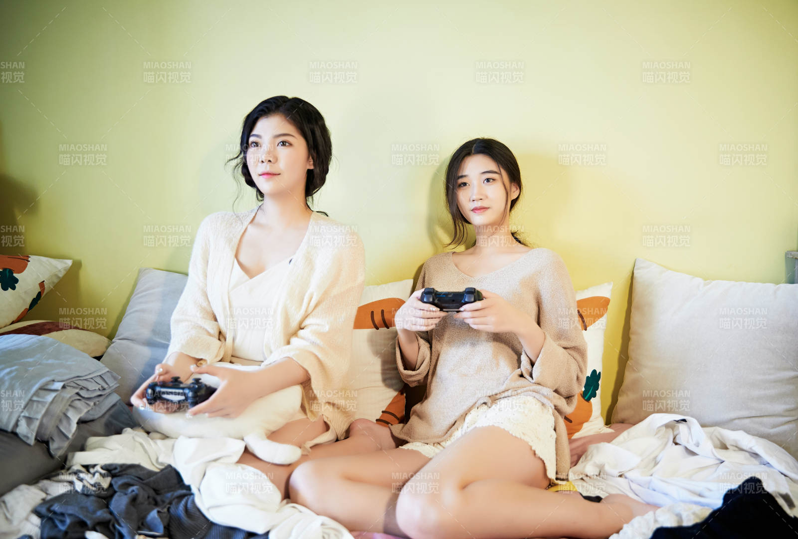 坐在床上打電玩的倆位美女