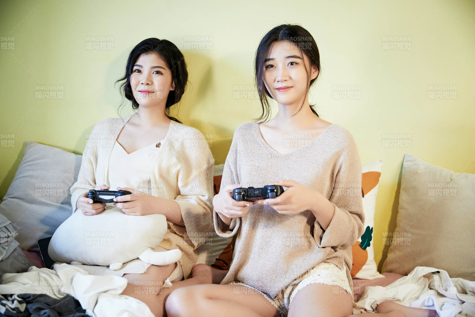 坐在床上打電玩的倆位美女