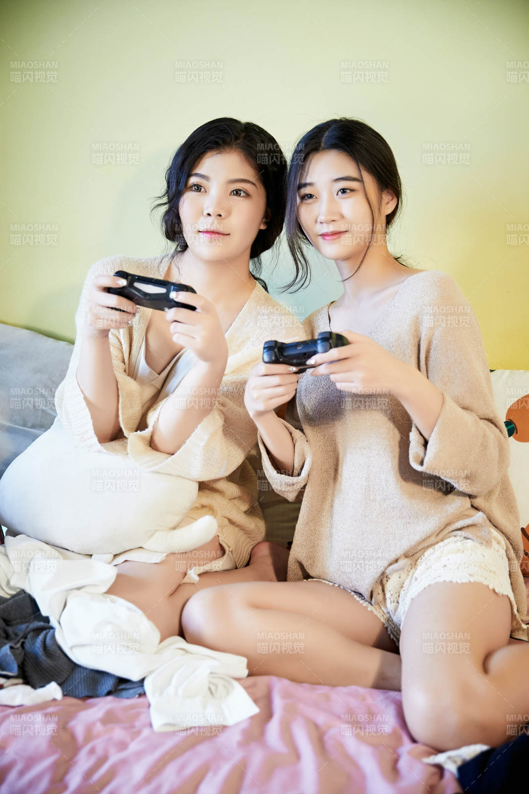 坐在床上打電玩的倆位美女