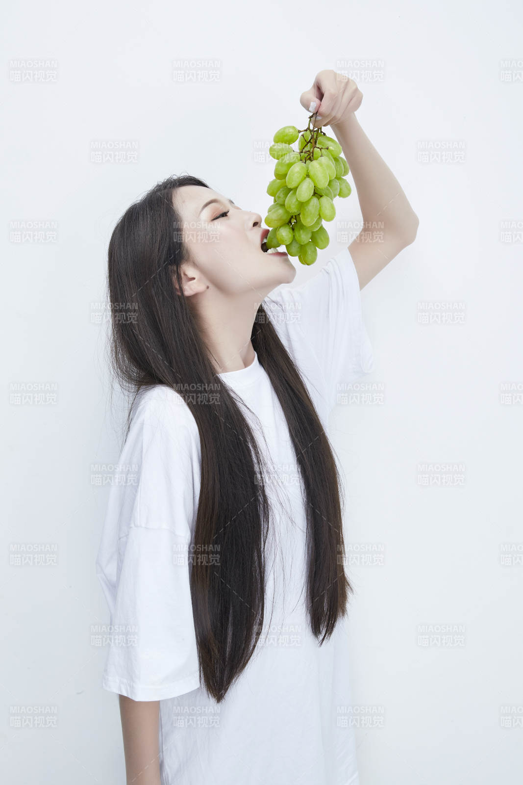 吃葡萄的穿白色長T血衫的長發可愛少女人像