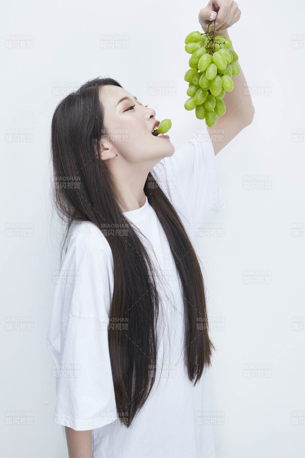 吃葡萄的穿白色長(zhǎng)T血衫的長(zhǎng)發(fā)可愛少女人像