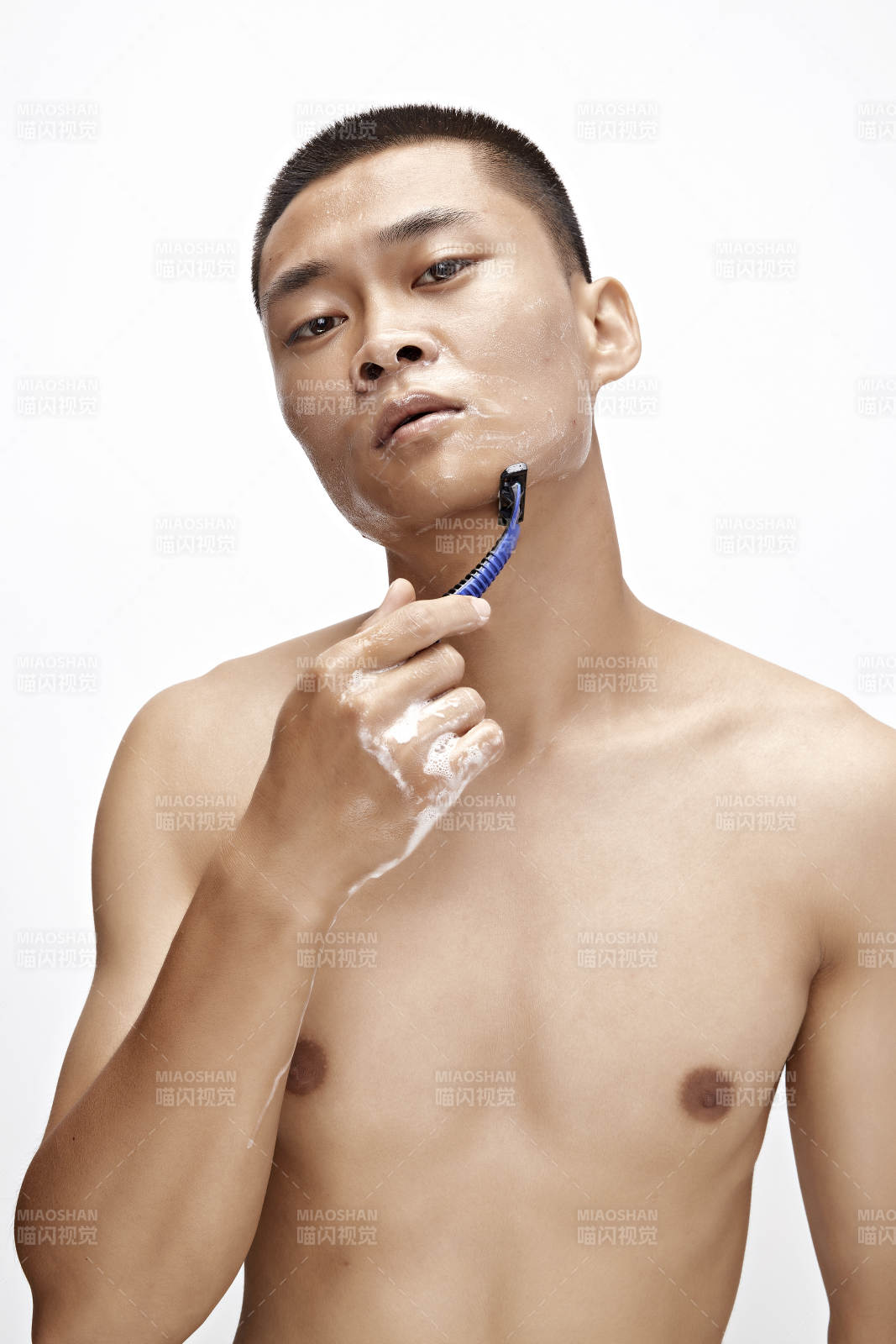 白色背景下手持剃须刀在刮胡子的亚洲男性