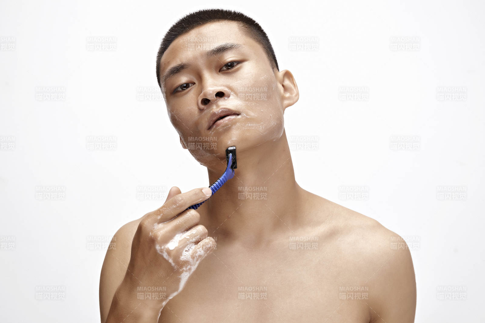 白色背景下手持剃須刀在刮胡子的亞洲男性