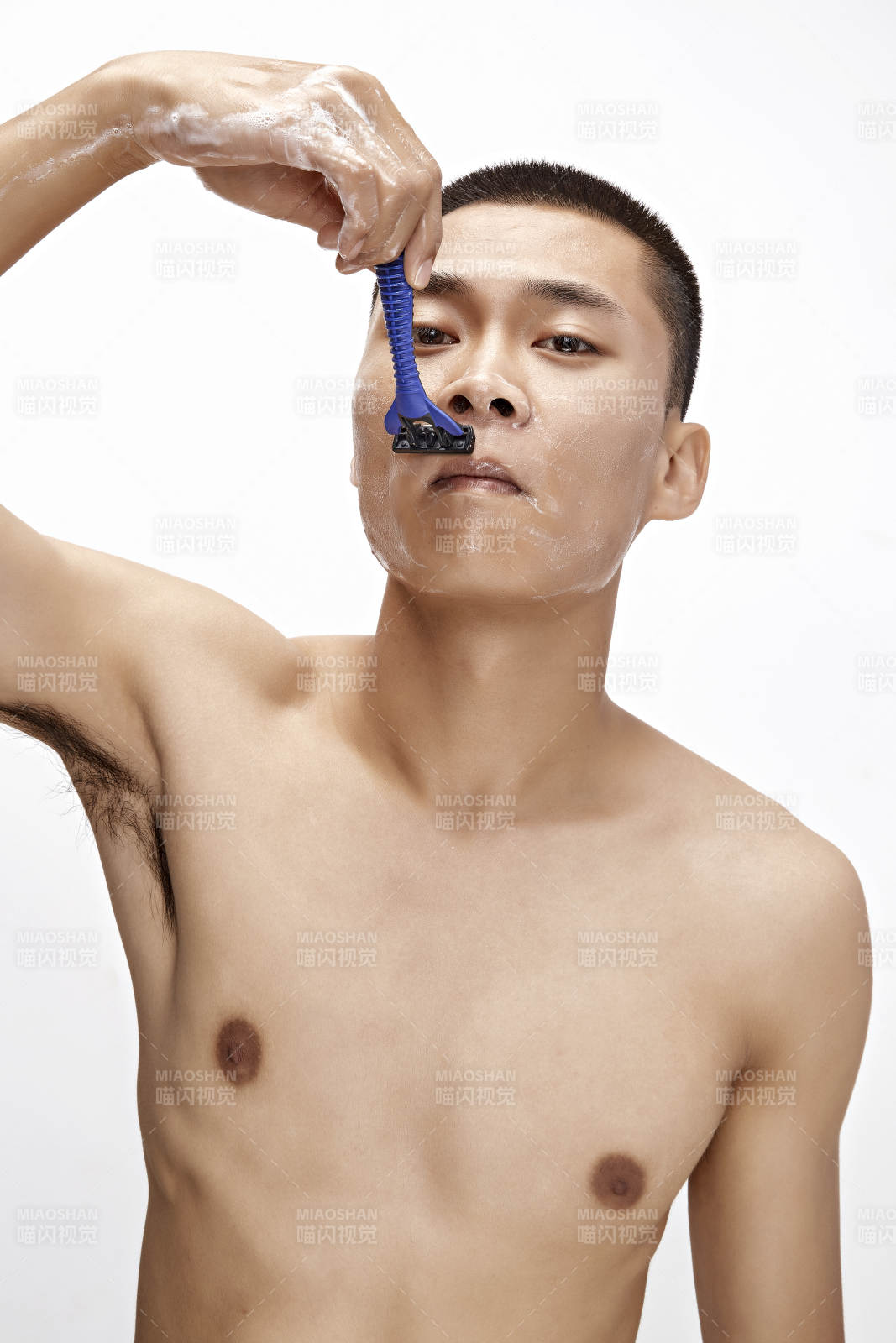 白色背景下手持剃須刀在刮胡子的亞洲男性