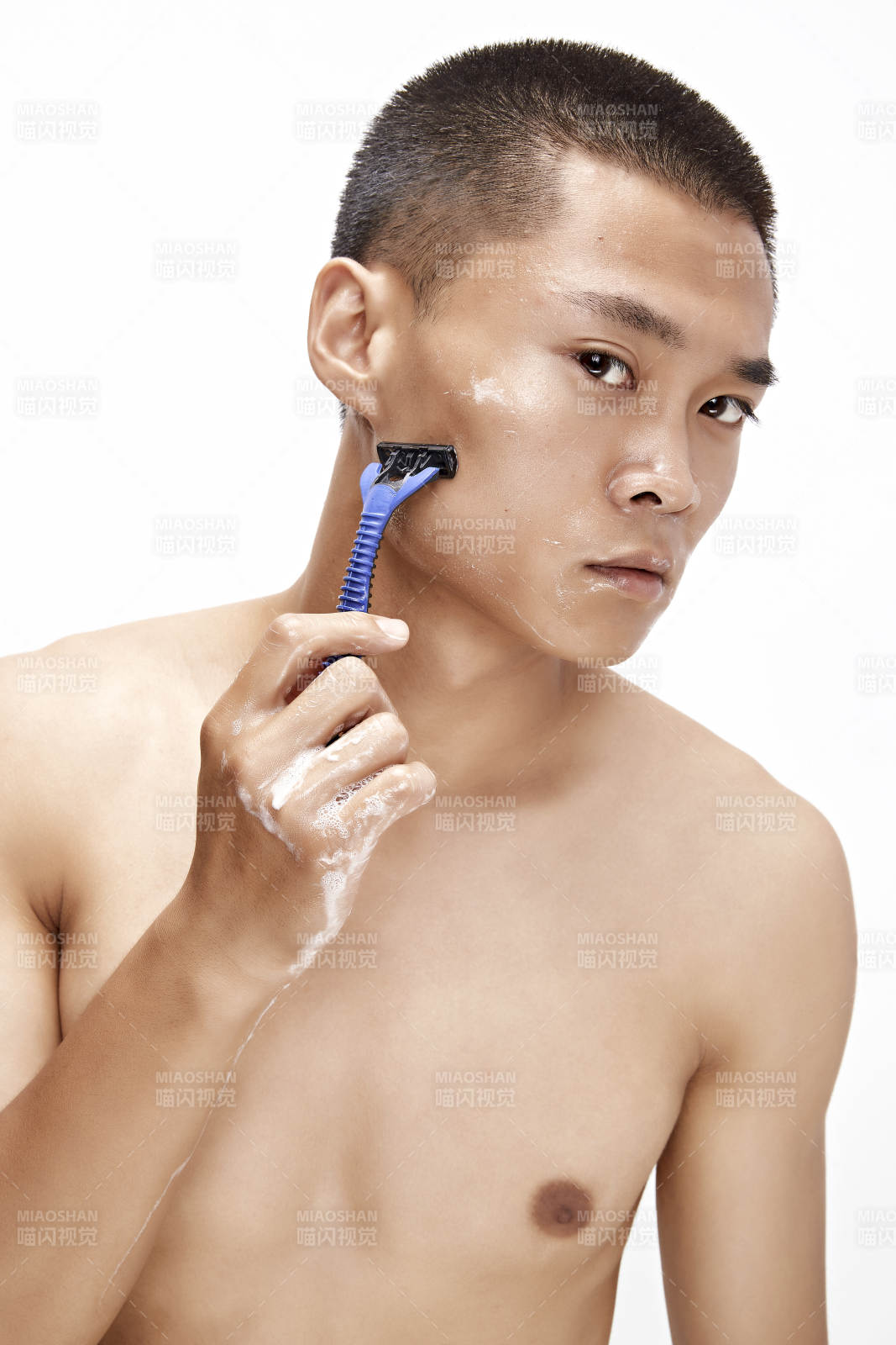 白色背景下手持剃须刀在刮胡子的亚洲男性