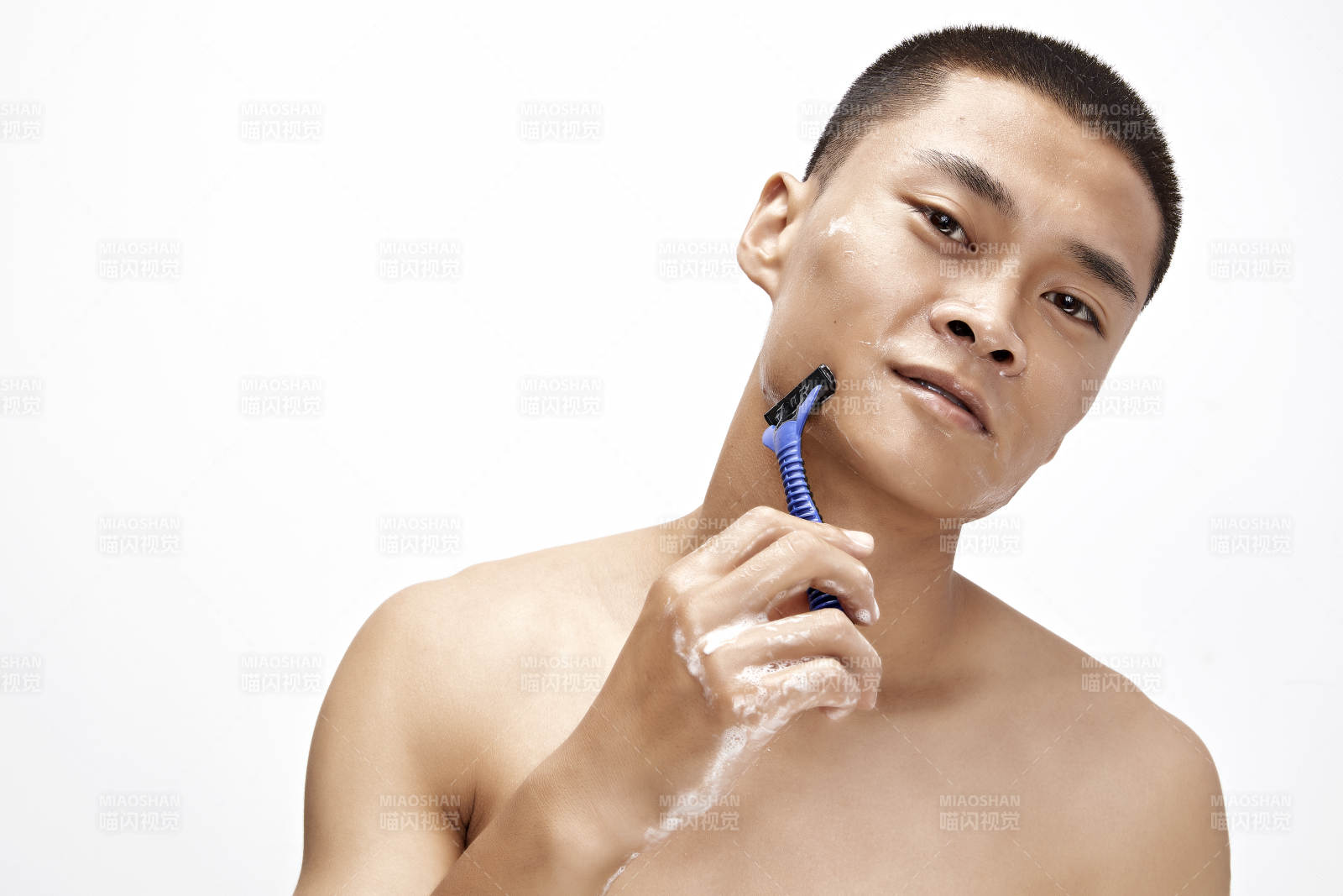 白色背景下手持剃须刀在刮胡子的亚洲男性