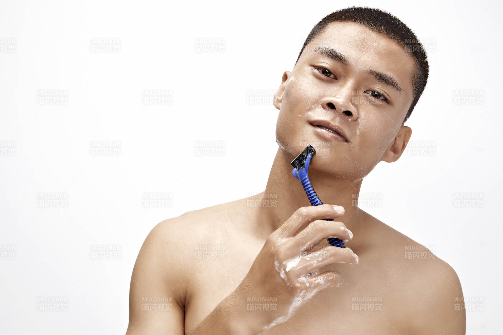 白色背景下手持剃須刀在刮胡子的亞洲男性