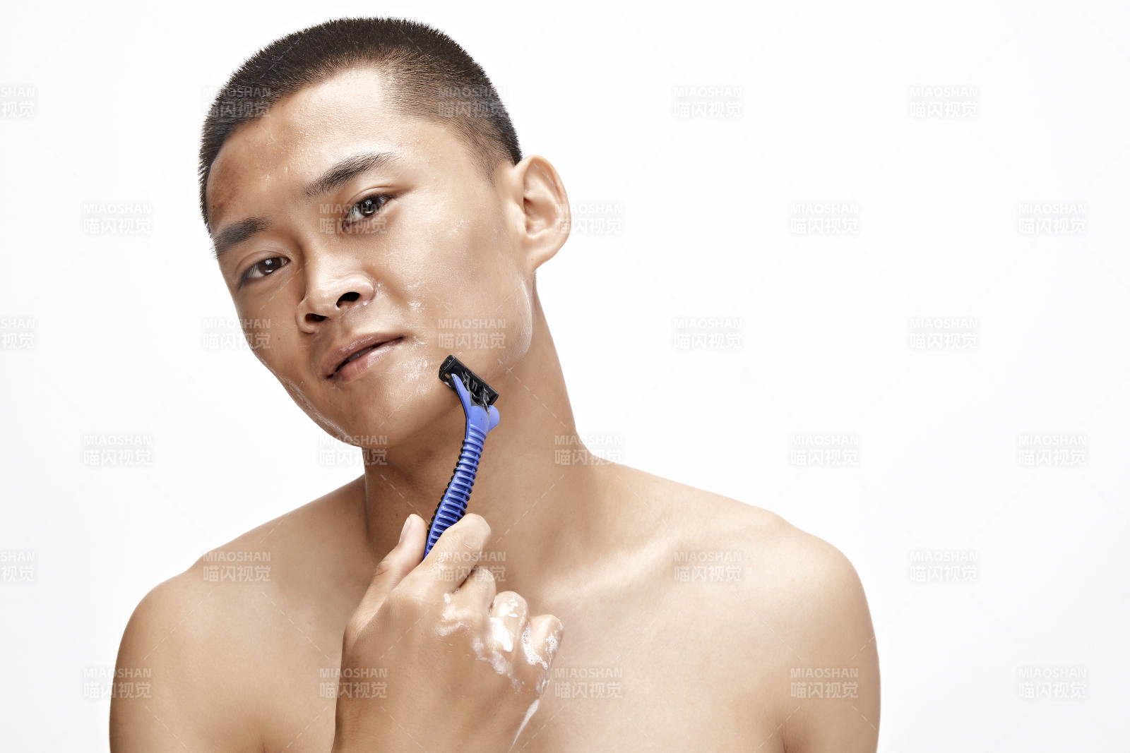 白色背景下手持剃须刀在刮胡子的亚洲男性