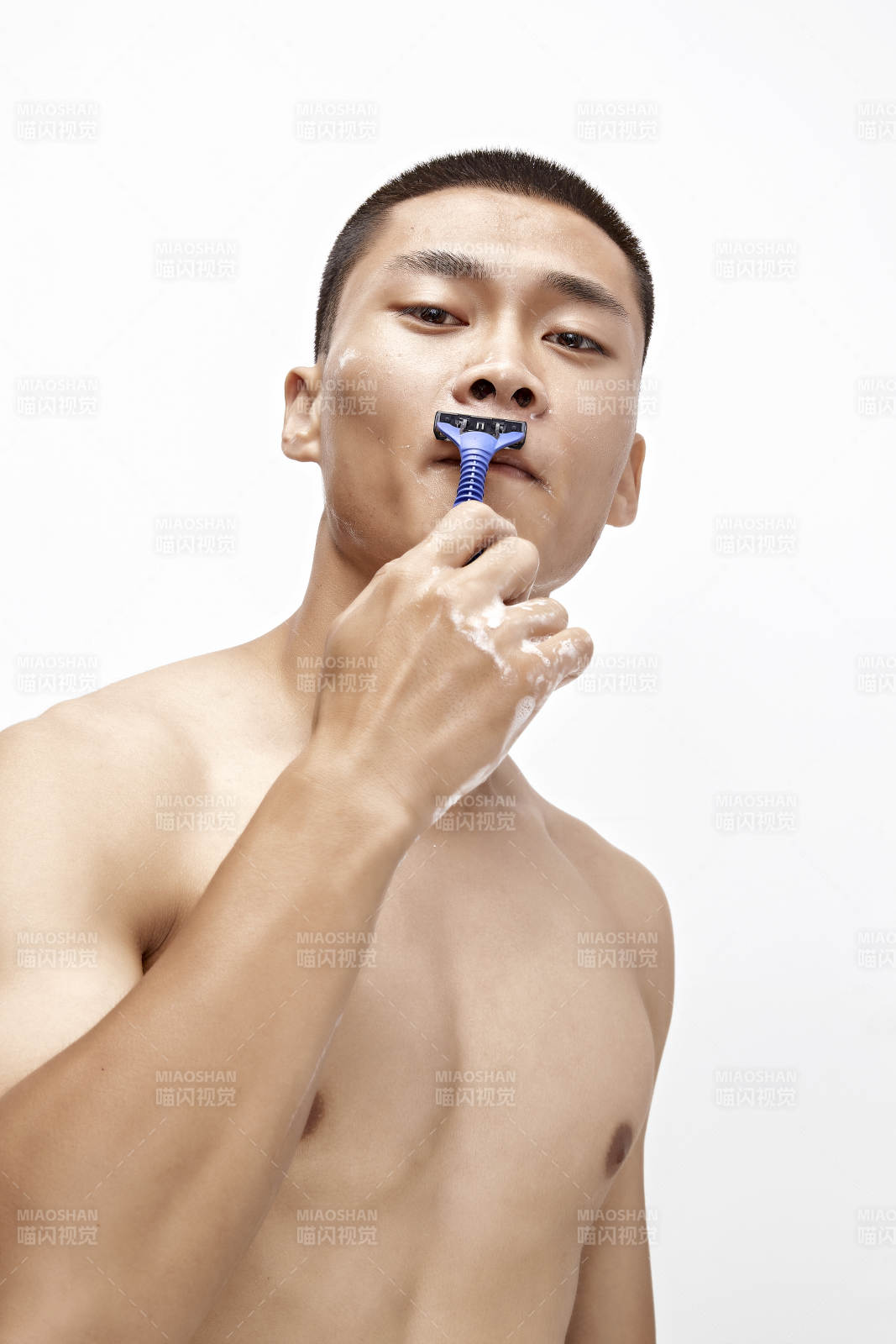 白色背景下手持剃須刀在刮胡子的亞洲男性