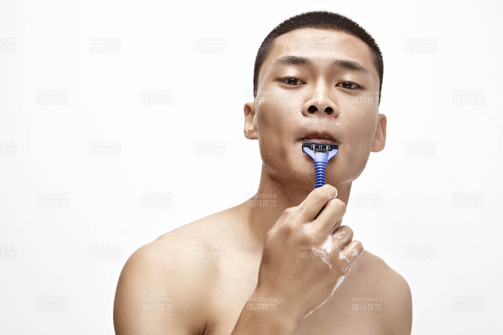 白色背景下手持剃須刀在刮胡子的亞洲男性