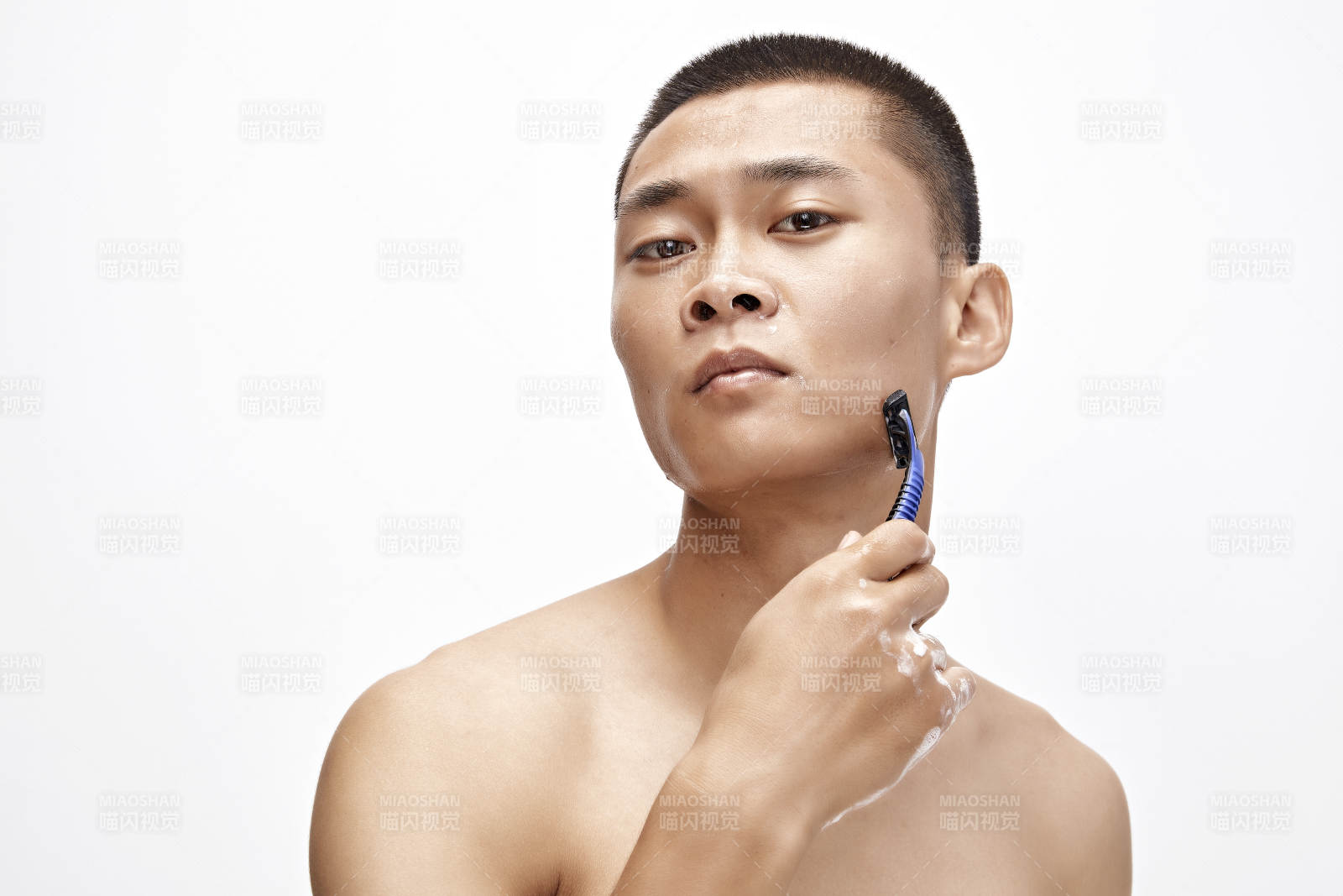 白色背景下手持剃須刀在刮胡子的亞洲男性