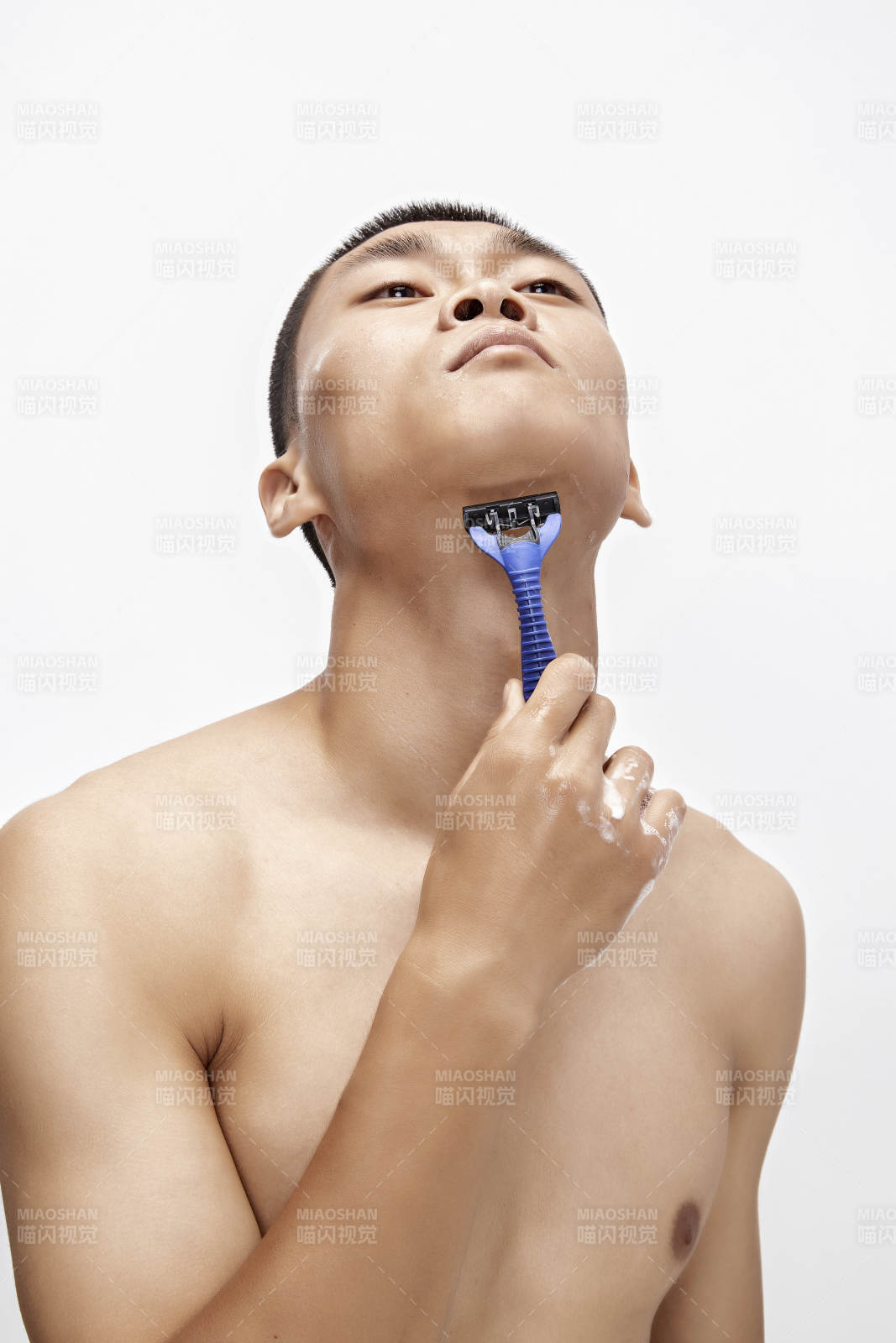 白色背景下手持剃須刀在刮胡子的亞洲男性