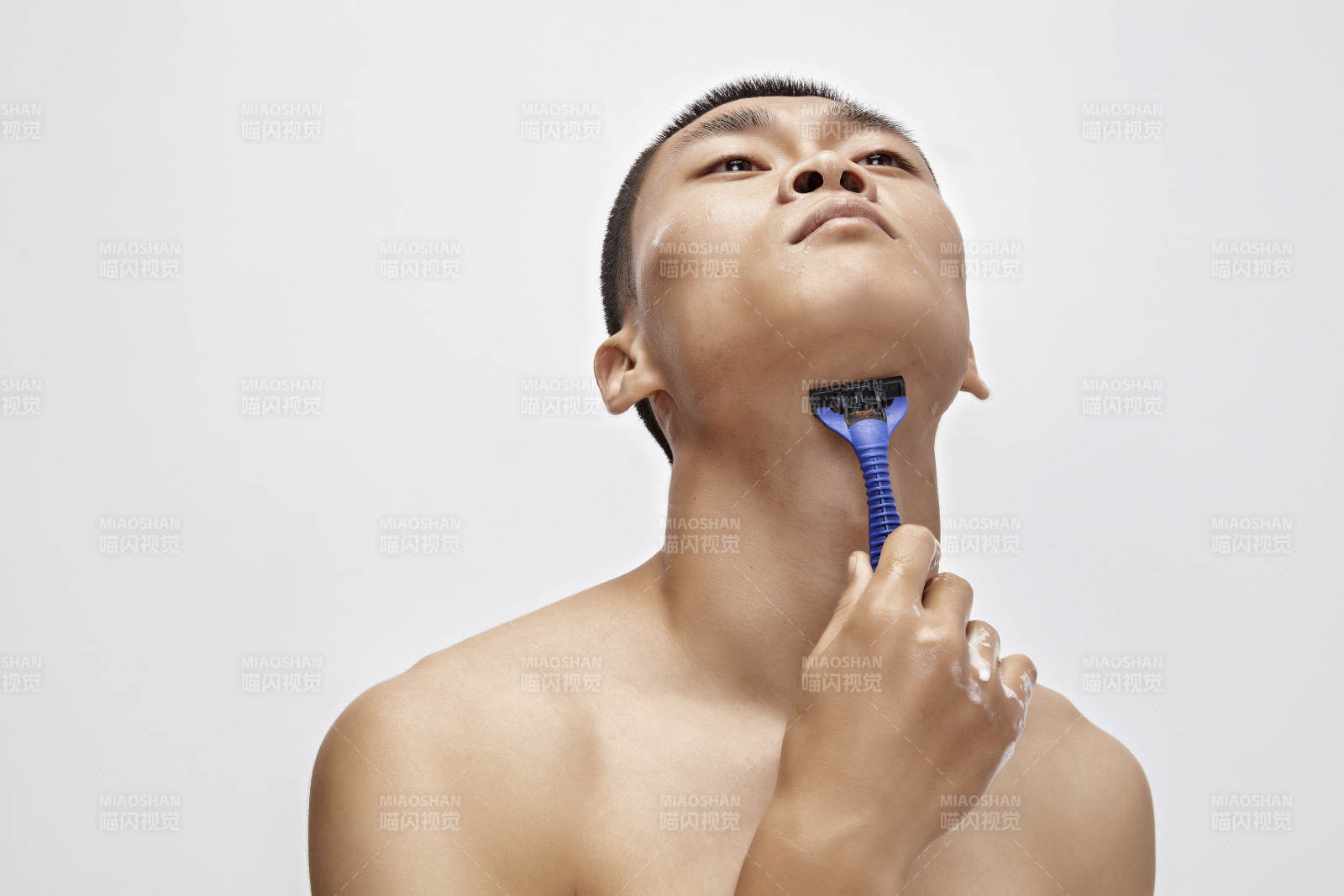 白色背景下手持剃須刀在刮胡子的亞洲男性