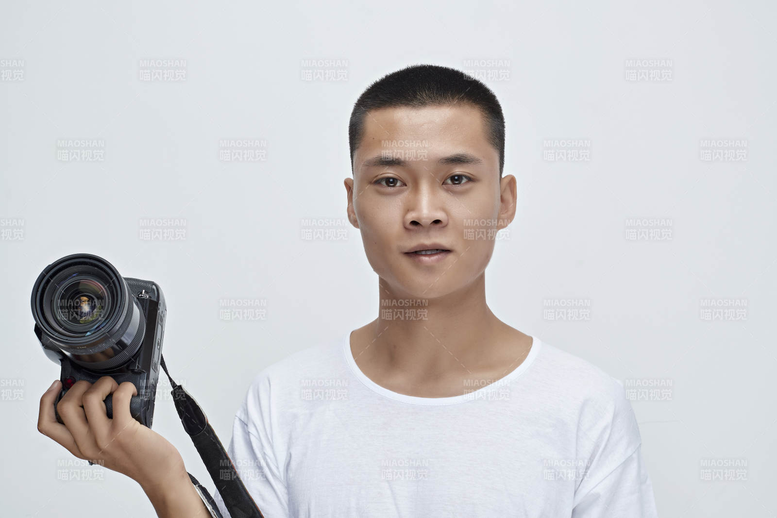 白色背景下手持照相机的亚洲男性摄影师