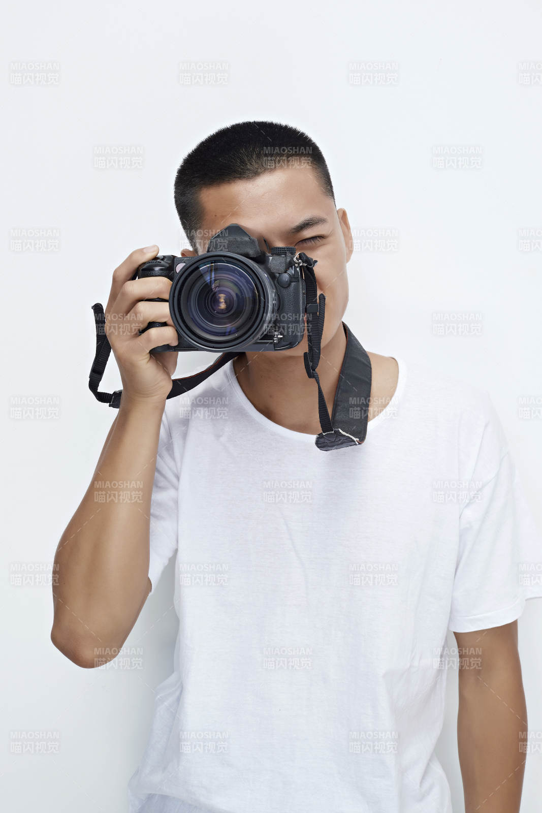 白色背景下手持照相機(jī)的亞洲男性攝影師